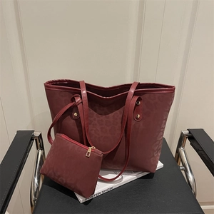 Retro burgundy leopard print tote bag set with matching small pouch on a leather chair