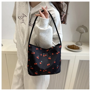 Detail shot of a black tote bag with red cherry print featuring slim shoulder straps
