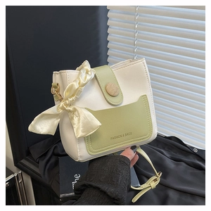 Detail einer kontrastfarbenen Eimertasche mit grüner Tasche und dekorativem Seidenschal