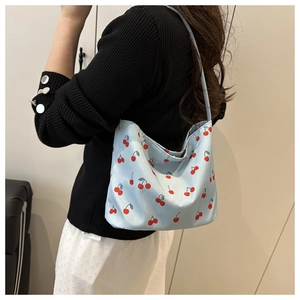 Detail of light blue hobo bag with red cherry print and slender shoulder strap