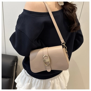 Détail d'un sac à bandoulière beige avec boucle dorée et lanière en cuir sur modèle