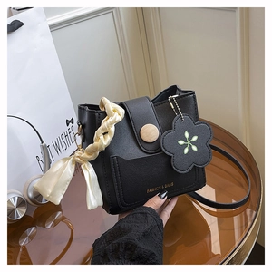Detail of black leather bucket bag with wooden ornament and elegant silk scarf on handle