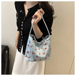 Close-up of light blue nylon shoulder bag featuring a vibrant red cherry print pattern