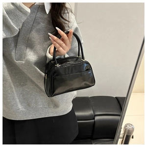 Details einer hochglänzenden schwarzen Mini-Handtasche mit goldenen Metallringen