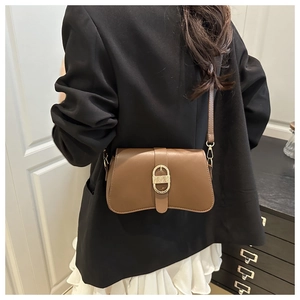 Brown retro underarm bag with gold oval buckle shown on a model in a minimal setting