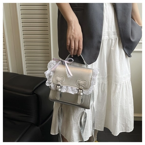 Détail du sac à main métallisé argenté avec dentelle blanche et nœud rose stylé