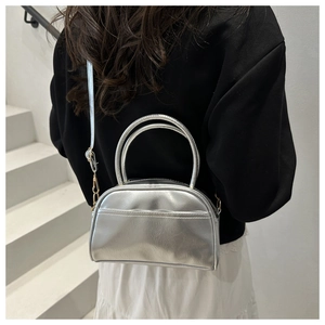 Detailansicht der silbernen Metallic-Handtasche in Kombination mit einem Outfit