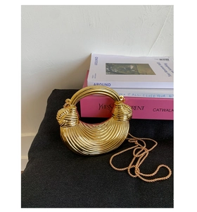 Detail of golden acrylic mini evening clutch with radial pleats and metal ring handle