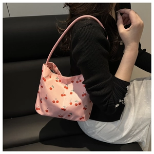 Detail of pink hobo bag with cherry print worn over the shoulder by a model