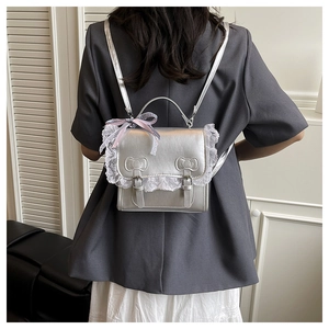 Détail du sac à dos en cuir argenté avec bordure en dentelle et nœuds décoratifs