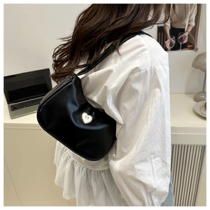 Side view of black hobo bag with heart bow metal detail worn with white ruffled top