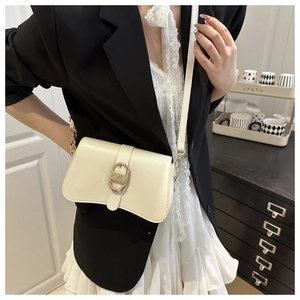 Gros plan détaillé du sac selle crème avec boucle dorée vintage et texture en cuir raffiné