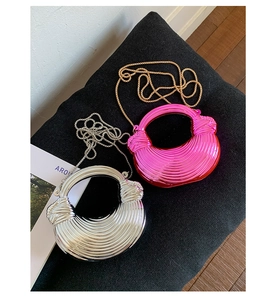 Detail view of metallic spiral-knot box bags in silver and magenta with chain straps