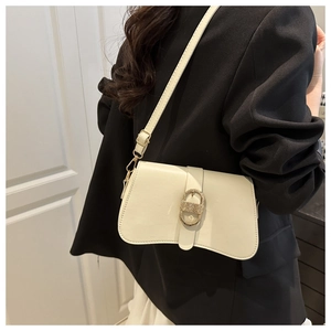Dettaglio borsa a busta bianco off-white con fibbia dorata testurizzata su blazer nero