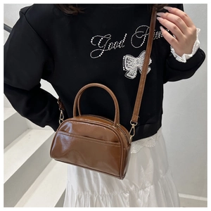 Details der glänzenden braunen Handtasche mit goldenen Beschlägen und Schultergurt