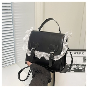 Détail du sac en cuir noir avec bordure en dentelle blanche et boucles à nœuds