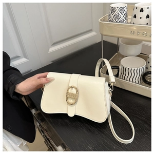 Detailansicht der cremefarbenen Ledertasche mit goldener Metallschnalle und verstellbarem Gurt