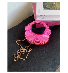 Macro shot of fuchsia metallic pleated dumpling bag with knot handle and gold chain