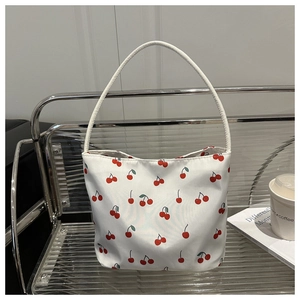 Close-up of white canvas tote bag featuring cute red cherry patterns on a modern chair