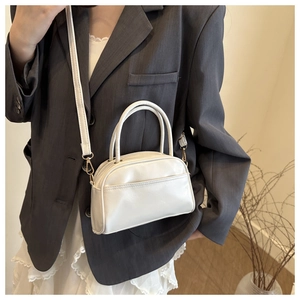 Detail der cremeweißen PU-Lederhandtasche mit goldenen Beschlägen und Schultergurt