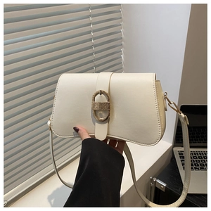 Close-up of cream underarm bag featuring a textured oval gold clasp and leather strap