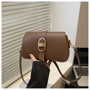 Detail of a brown leather shoulder bag with vintage gold metal buckle and hourglass shape