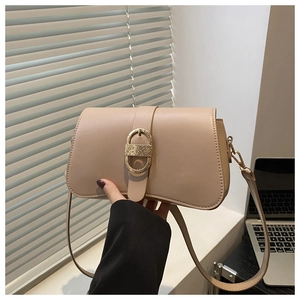 Detail of beige shoulder bag with a textured oval golden metallic buckle in natural light