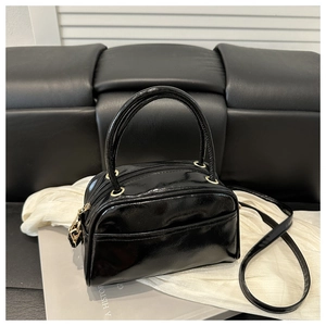Detail der schwarzen Lackleder-Handtasche mit goldener Hardware und Doppelreißverschluss