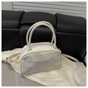 Detailansicht einer weißen Mini-Handtasche mit goldener Hardware und Rundgriffen auf Stoff