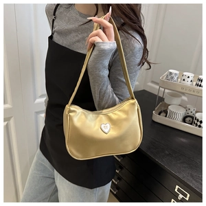 Detailed view of golden metallic crescent bag with heart emblem and sparkling crystals