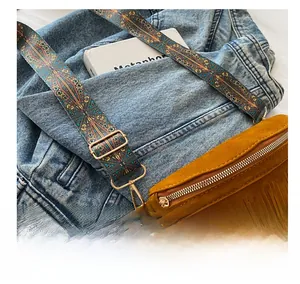 Détail de la boucle en métal et bandoulière tissée du sac marron à franges