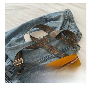 Détail d'une bandoulière tissée bohème et de franges sur un sac à bandoulière marron