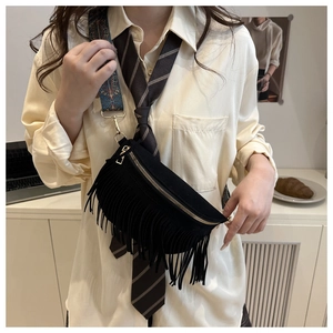 Close-up of black fringe crossbody bag with suede texture and ethnic woven strap