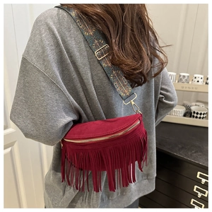 Détail du sac bandoulière bordeaux en daim avec franges et sangle bohème sur modèle