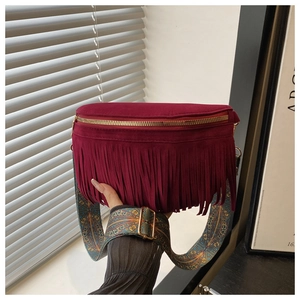Close-up of burgundy suede fringe bag with bohemian strap and gold metallic zipper