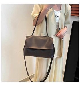 Detail of a large dark brown leather shoulder bag with flap closure and soft matte finish