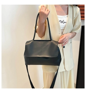 Detail of black matte leather shoulder bag with rounded lines and flap closure