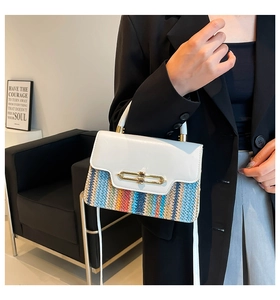 Detail of color-block flap bag featuring woven stripe texture and gold metal buckle