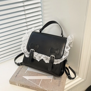 Sac à dos en similicuir noir avec dentelle, boucles argentées et nœuds sur décor chic