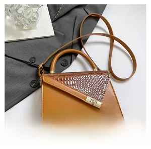 Detail of brown croc-embossed leather handbag with gold turn-lock and adjustable strap