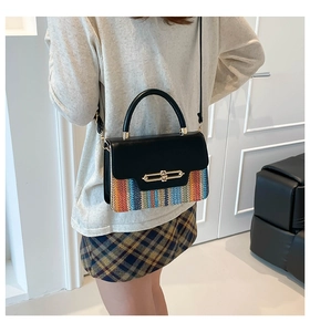 Close-up of stylish contrast handbag with black leather and colorful woven pattern