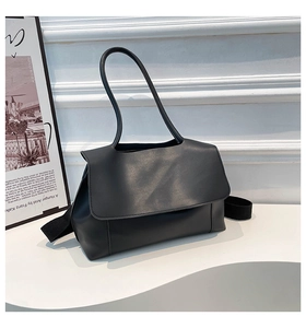 Detail of minimalist black leather tote bag featuring a textured strap and elegant stitching