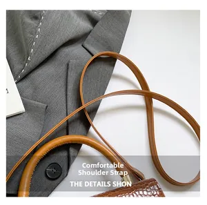 Detail of comfortable shoulder strap and textured stone pattern on brown handbag