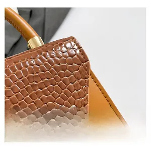 Detail of brown crocodile pattern leather handbag with polished gold-tone metal hardware