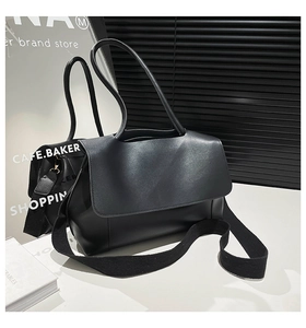 Detail of minimalist black leather tote bag with round handle and wide fabric strap