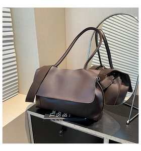 Detail of a dark brown matte leather shoulder bag on a minimalist black side table decor