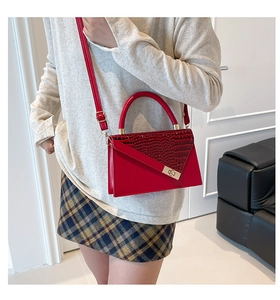 Detail of red crocodile texture flap handbag with gold metal twist lock and shoulder strap