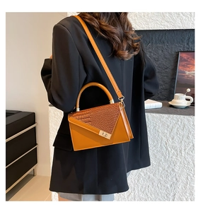 Close-up of brown handbag featuring crocodile texture mix and metal twist lock detail