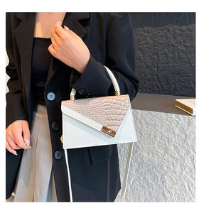 Detail of white and beige crocodile embossed pattern with golden twist lock on handbag