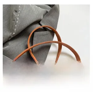 Detail of adjustable brown leather shoulder strap with gold buckle on gray blazer